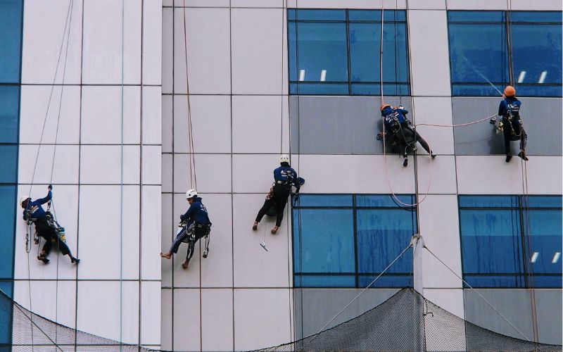 Limpador de vidros cai de prédio e atinge pedestre, imagem mostra cinco homens limpando janela de prédio